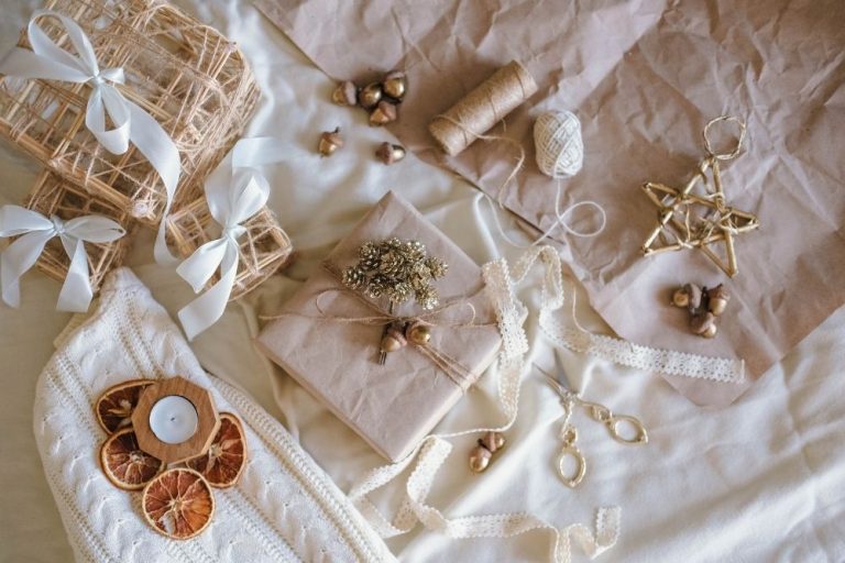 Thoughtful gifts under £30 arranged on soft neutral fabric with wrapped presents, ribbon and cosy textures
