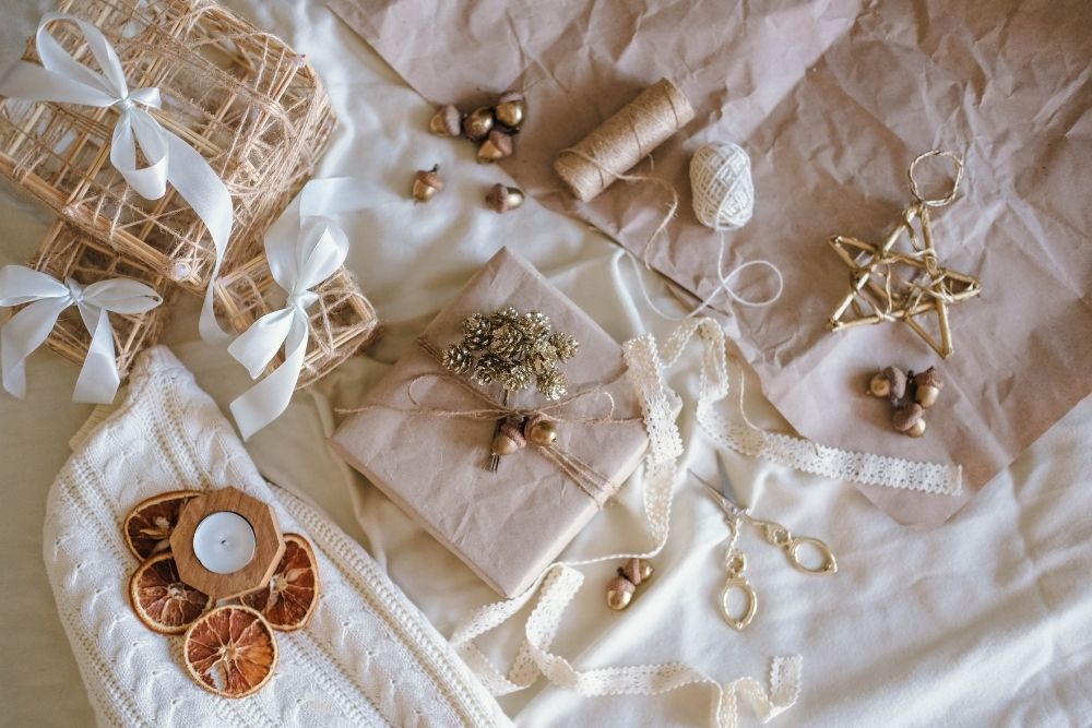 Thoughtful gifts under £30 arranged on soft neutral fabric with wrapped presents, ribbon and cosy textures